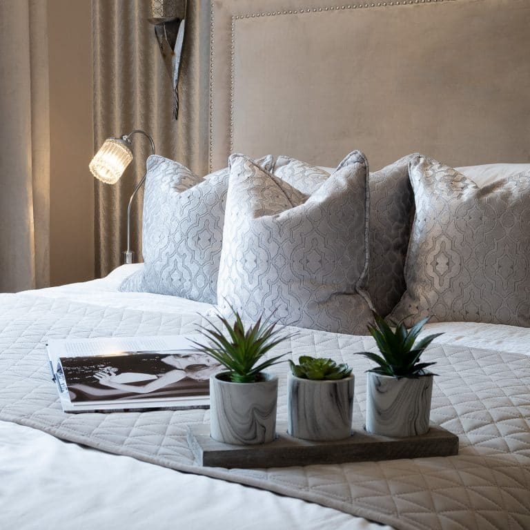 Neutral Bedding on Bed with Plants and Book